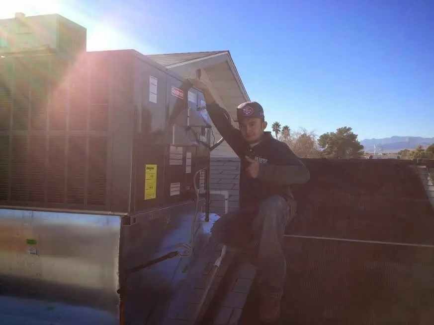 HVAC technician performing AC Tune-Up on a rooftop unit in Madison Heights