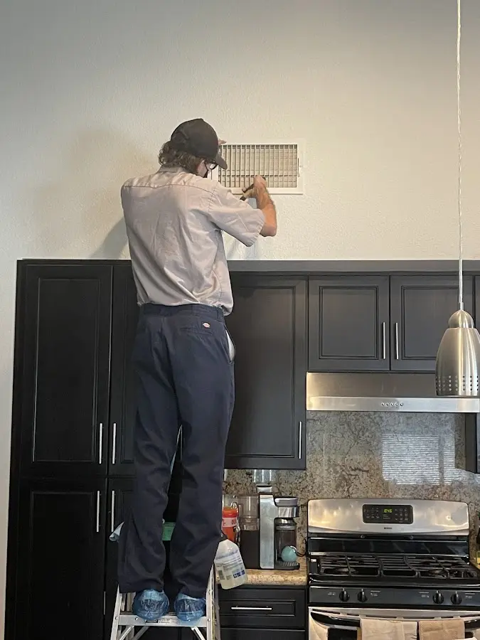 Technician inspecting an air vent during HVAC service in Madison Heights